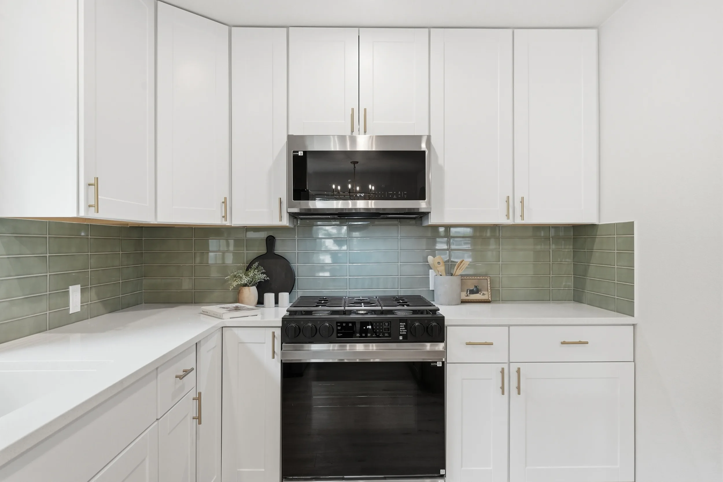 Range wall with white shaker cabinets and sage tile backsplash