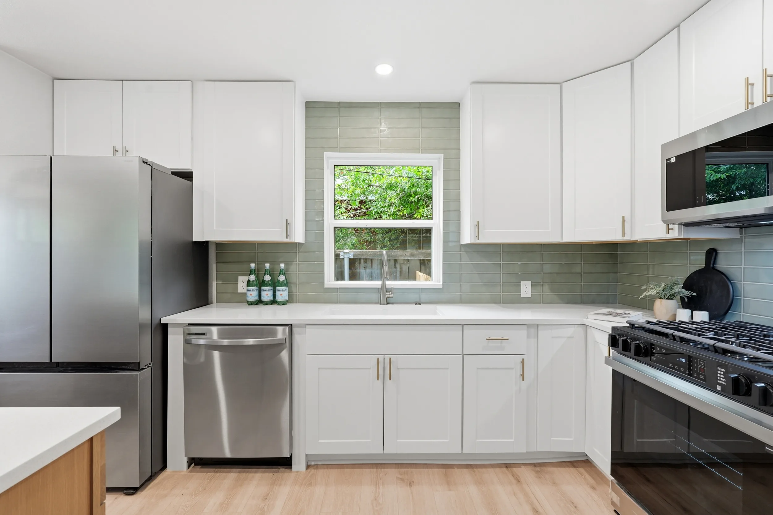 Sage tile backsplash around the sink window