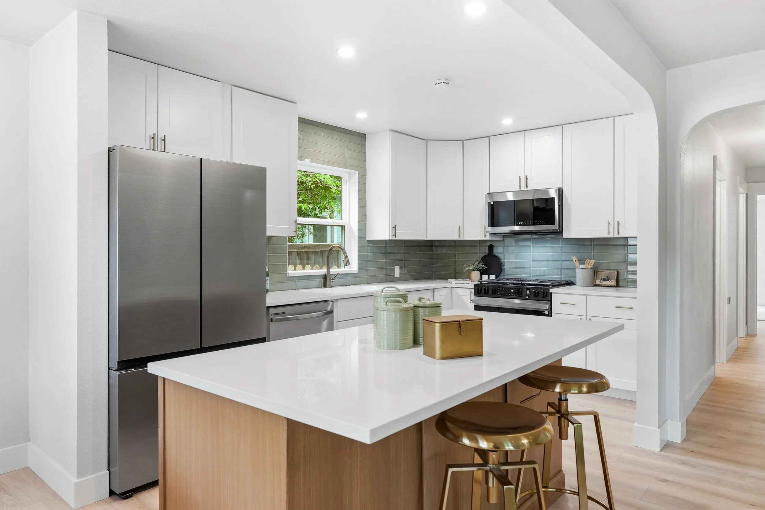 Kitchen with white shaker cabinets, quartz island and stainless appliances